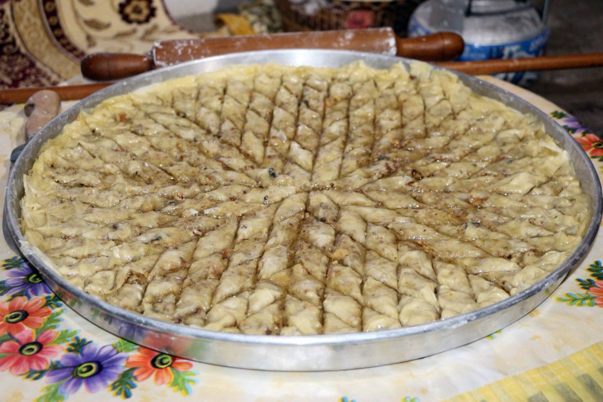 <strong>EV YAPIMI BAKLAVA NASIL YAPILIR?</strong>
Bir kabın içerisine 3 adet yumurtayı kırıp üzerine bir su bardağı sütü bir su bardağı sıvı yağı ,bir tatlı kaşığı sirkeyi ve yarım çay kaşığı tuzu ekleyip karıştırıp üzerine aldığı kadar un ilave ediyoruz. Kulak memesi yumuşaklığında bir hamur elde edene kadar hamuru güzelce yoğuruyoruz. Kulak memesi yumuşaklığında yoğurduğumuz hamuru 30 eşit parçaya ayırarak hamurları (ceviz büyüklüğünde) güzelce yuvarlıyoruz. Yuvarladığımız hamurlardan 1 tane alıp üzerine mısır nişastası serpip oklava yardımı ile bir küçük tabak büyüklüğünde açarak kenarda bekletiyoruz. Diğer kalan hamurları da aynı şekilde oklava ve mısır nişastası yardımı ile bir küçük tabak büyüklüğünde açıp üst üste onar onar biriktiriyoruz. İlk on parçayı nişasta ve oklava yardımı ile bir fırın tepsisi büyüklüğünde yufka şekli veriyoruz.