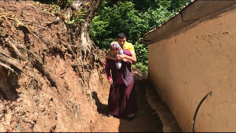 Yolu olmayan evine engelli oğlunu sırtında götürüyor