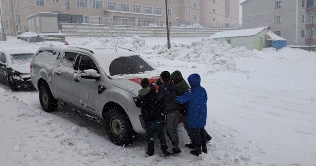 Çocuklar, bir aracın önündeki Türk bayrağının üzerindeki karı temizledi