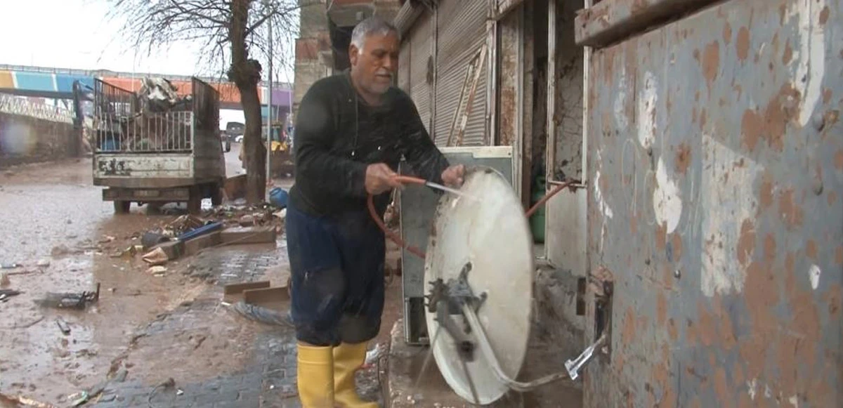 Sağanak ve sele aldırış etmeden hortumla anten yıkadı